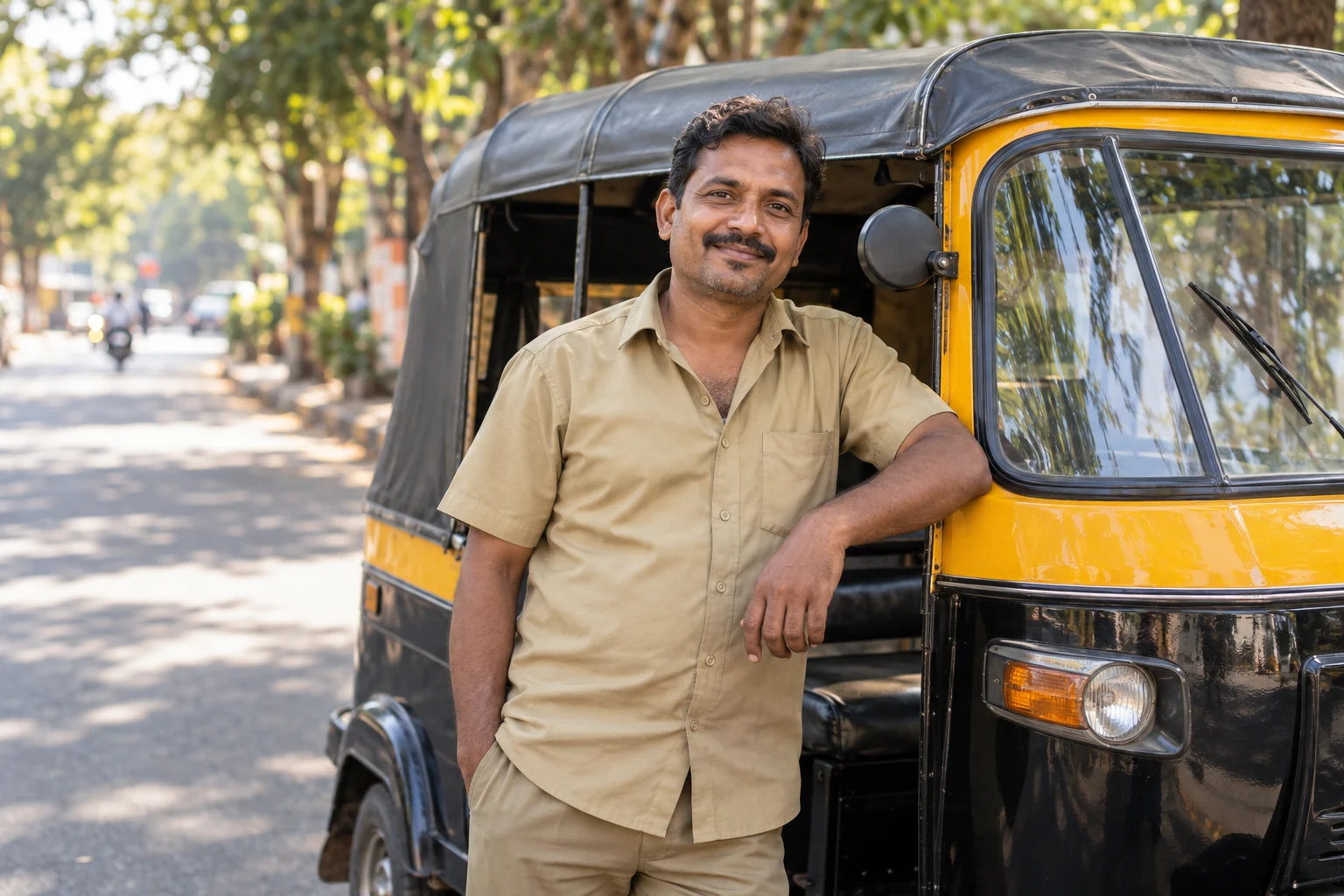 A driver standing proudly beside an auto-rickshaw
